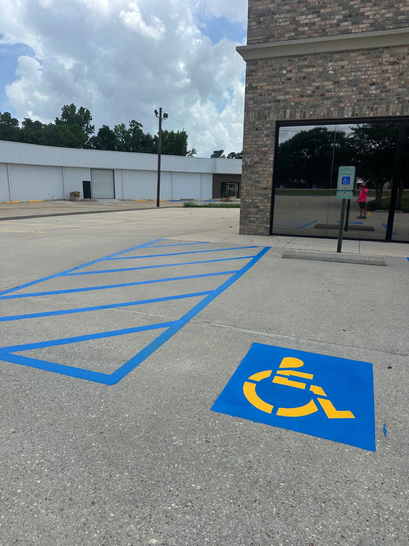 Blue and yellow accessible parking symbol with a freshly striped access aisle