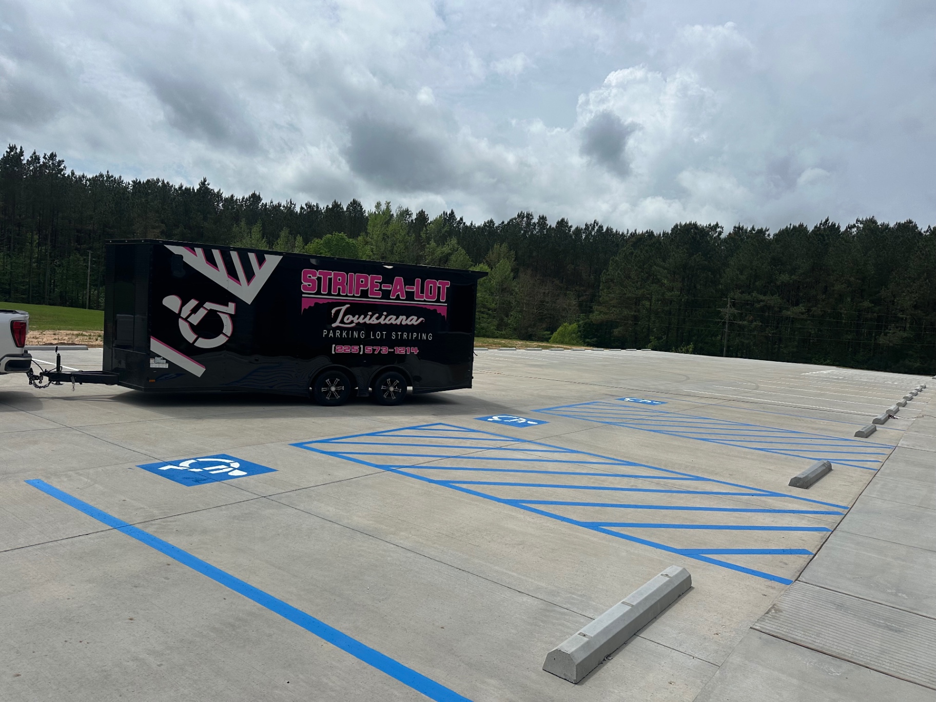 Fresh blue accessible parking spaces beside a Stripe-A-Lot trailer